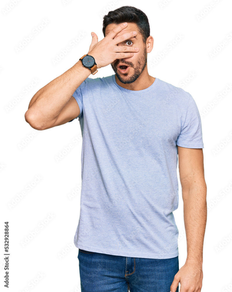 Young hispanic man wearing casual clothes peeking in shock covering face and eyes with hand, looking through fingers with embarrassed expression. Young hispanic man wearing casual clothes peeking in shock covering face and eyes with hand, looking through fingers with embarrassed expression.