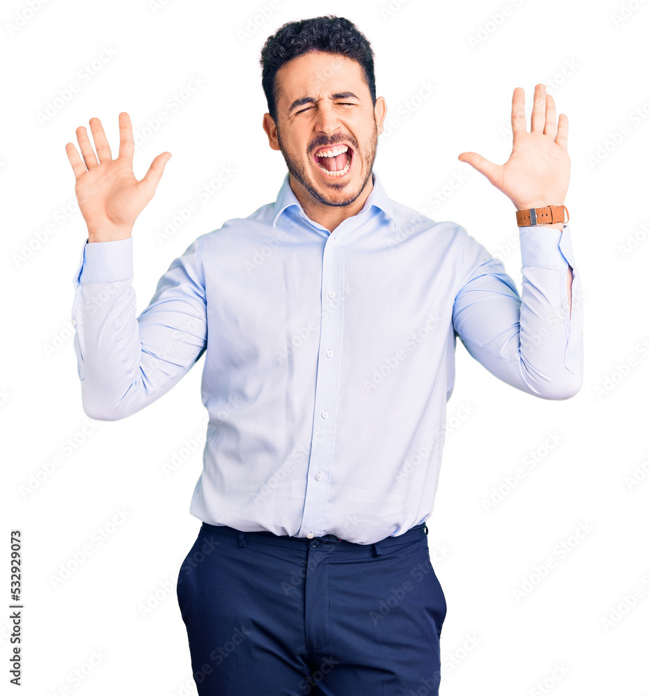 Fototapeta premium Young hispanic man wearing business clothes celebrating mad and crazy for success with arms raised and closed eyes screaming excited. winner concept