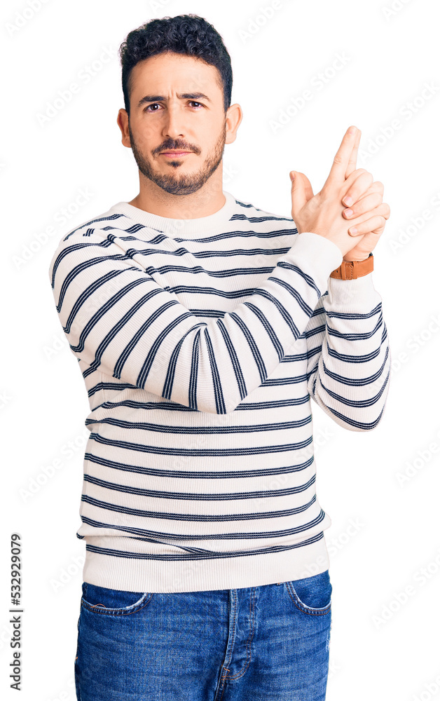 Young hispanic man wearing casual clothes holding symbolic gun with hand gesture, playing killing shooting weapons, angry face Young hispanic man wearing casual clothes holding symbolic gun with hand gesture, playing killing shooting weapons, angry face