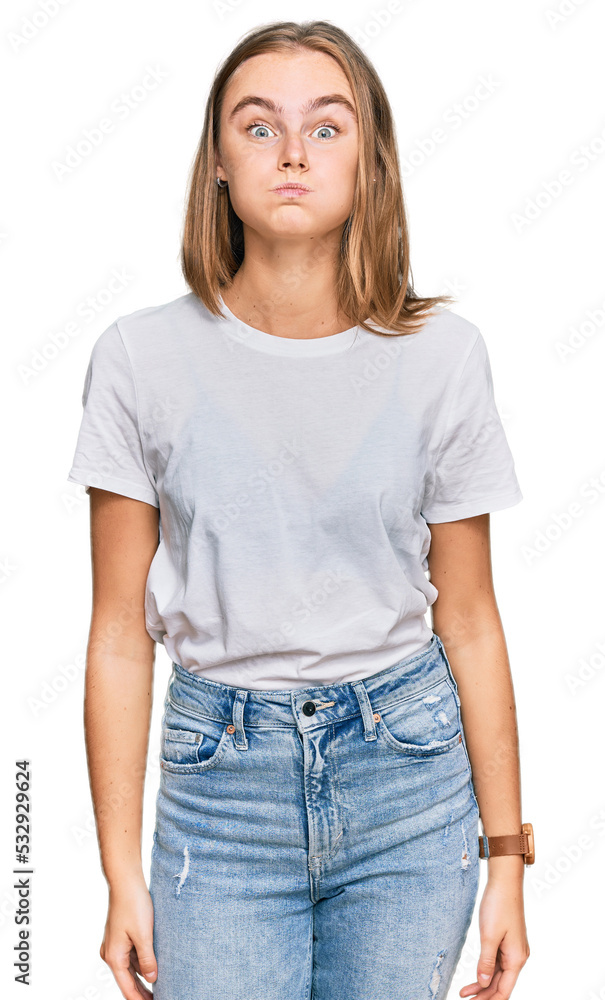 Obraz premium Beautiful young blonde woman wearing casual white t shirt puffing cheeks with funny face. mouth inflated with air, crazy expression.