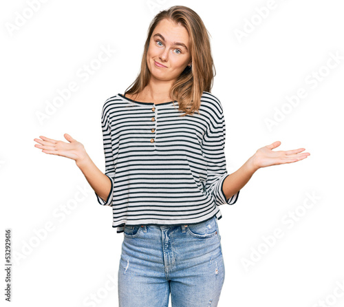 Beautiful blonde woman wearing casual clothes clueless and confused expression with arms and hands raised. doubt concept.