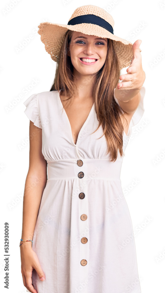 Young beautiful blonde woman wearing summer dress and hat smiling friendly offering handshake as greeting and welcoming. successful business. Young beautiful blonde woman wearing summer dress and hat smiling friendly offering handshake as greeting and welcoming. successful business.