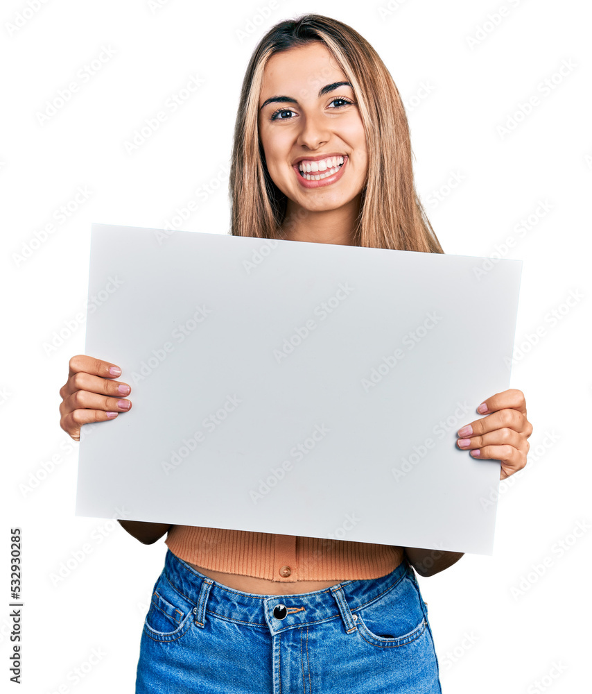 Hispanic young woman holding blank empty banner smiling with a happy and cool smile on face. showing teeth. Hispanic young woman holding blank empty banner smiling with a happy and cool smile on face. showing teeth.