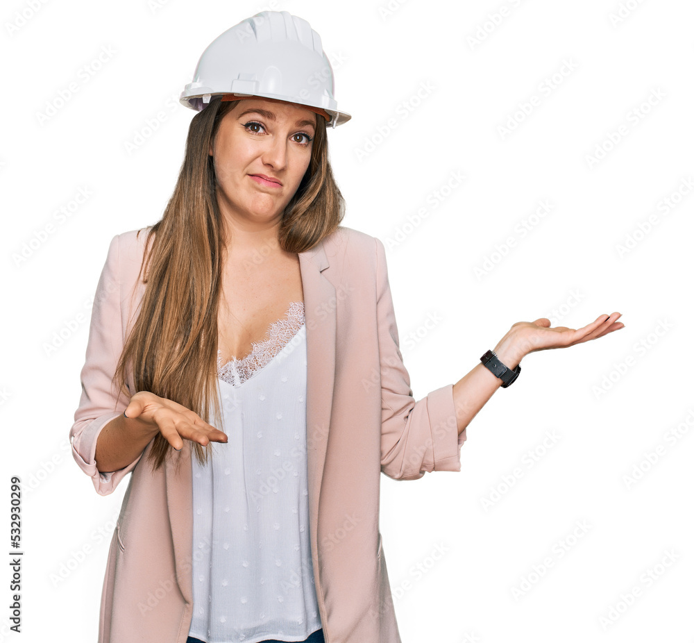 Young blonde woman wearing architect hardhat clueless and confused expression with arms and hands raised. doubt concept. Young blonde woman wearing architect hardhat clueless and confused expression with arms and hands raised. doubt concept.