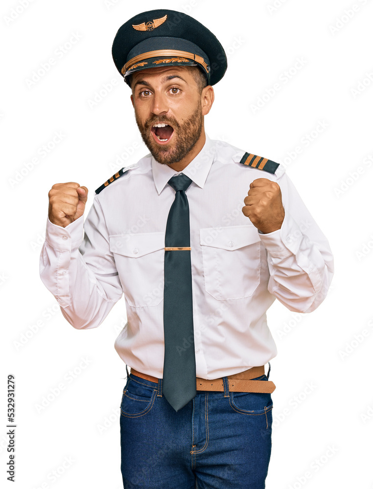 Handsome man with beard wearing airplane pilot uniform celebrating surprised and amazed for success with arms raised and open eyes. winner concept. Handsome man with beard wearing airplane pilot uniform celebrating surprised and amazed for success with arms raised and open eyes. winner concept.