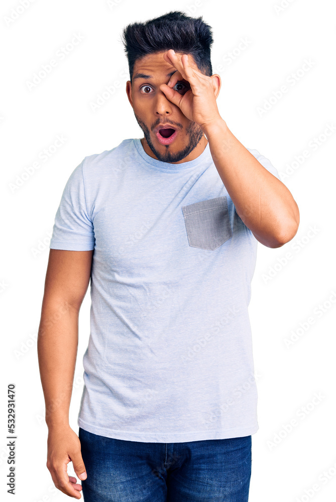 Fototapeta premium Handsome latin american young man wearing casual clothes doing ok gesture shocked with surprised face, eye looking through fingers. unbelieving expression.