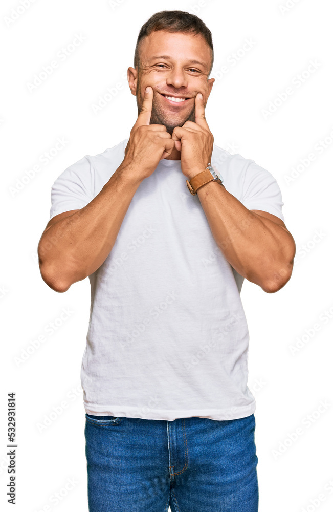Handsome muscle man wearing casual white tshirt smiling with open mouth, fingers pointing and forcing cheerful smile Handsome muscle man wearing casual white tshirt smiling with open mouth, fingers pointing and forcing cheerful smile