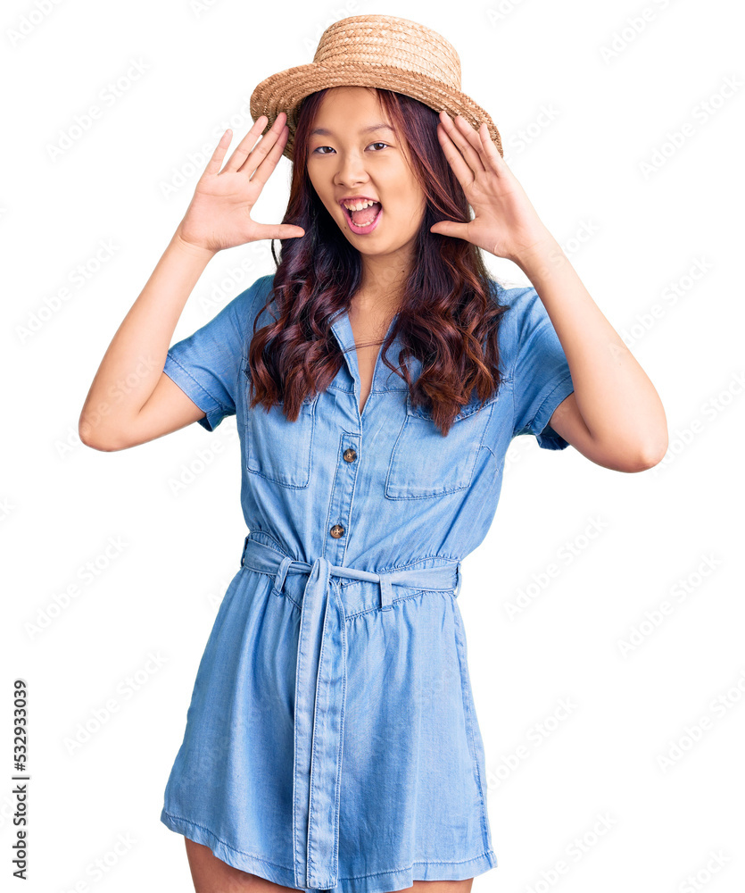 Young beautiful chinese girl wearing summer hat smiling cheerful playing peek a boo with hands showing face. surprised and exited Young beautiful chinese girl wearing summer hat smiling cheerful playing peek a boo with hands showing face. surprised and exited