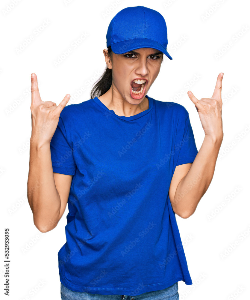 Young hispanic girl wearing delivery courier uniform shouting with crazy expression doing rock symbol with hands up. music star. heavy concept. Young hispanic girl wearing delivery courier uniform shouting with crazy expression doing rock symbol with hands up. music star. heavy concept.