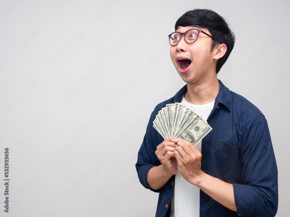 Positive man wear glasses feels amazed hold money looking at copy space Positive man wear glasses feels amazed hold money looking at copy space