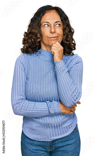 Middle age hispanic woman wearing casual clothes serious face thinking about question with hand on chin, thoughtful about confusing idea