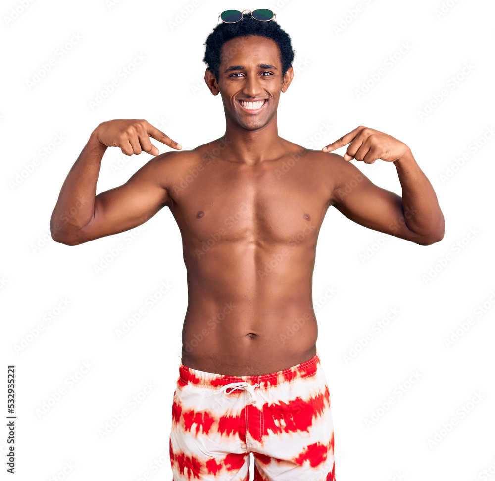 Fototapeta premium African handsome man wearing swimsuit and sunglasses looking confident with smile on face, pointing oneself with fingers proud and happy.