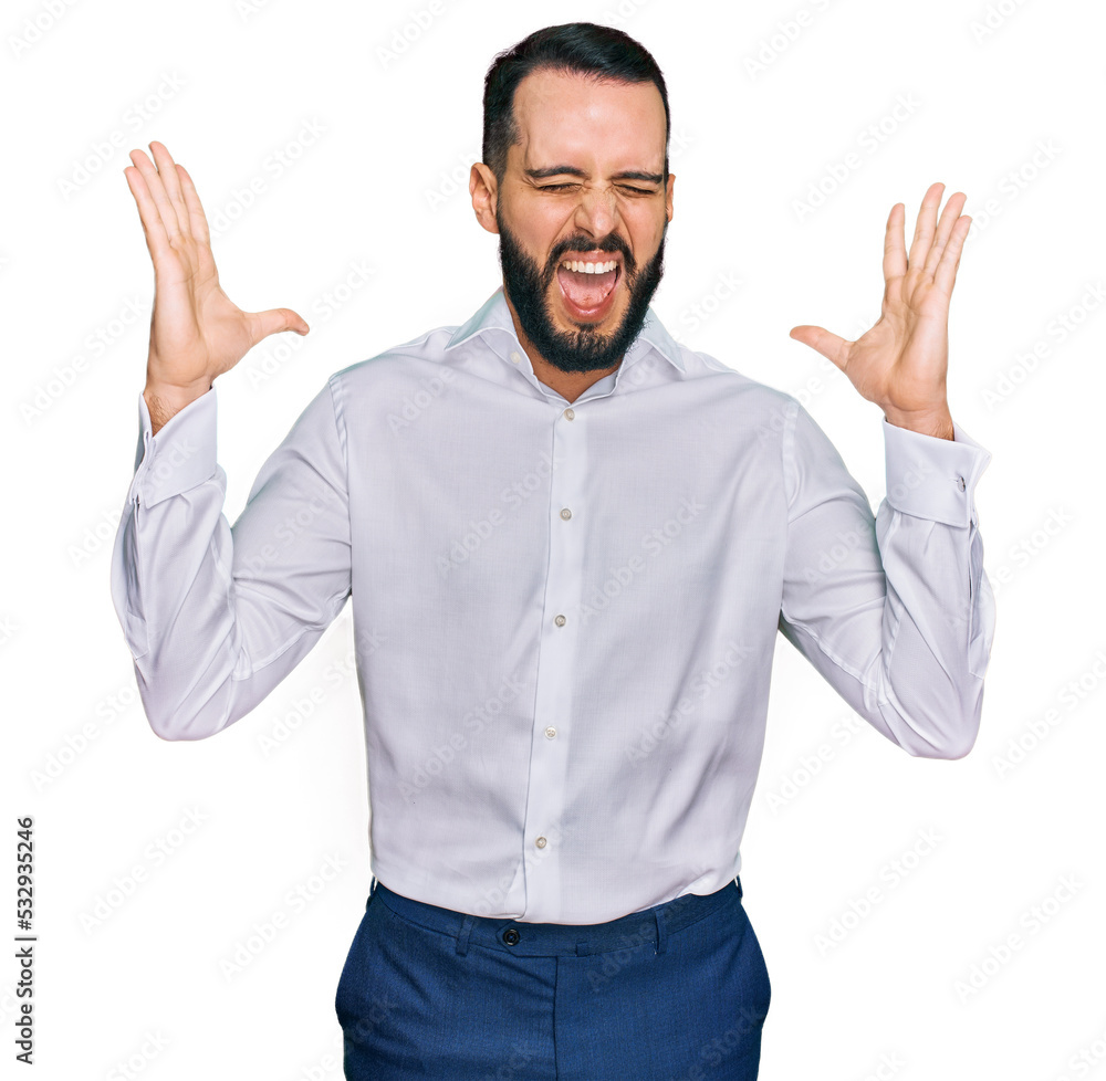 Young man with beard wearing business shirt celebrating mad and crazy for success with arms raised and closed eyes screaming excited. winner concept Young man with beard wearing business shirt celebrating mad and crazy for success with arms raised and closed eyes screaming excited. winner concept