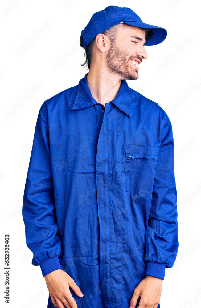 Young hispanic man wearing painter uniform looking away to side with smile on face, natural expression. laughing confident. Young hispanic man wearing painter uniform looking away to side with smile on face, natural expression. laughing confident.
