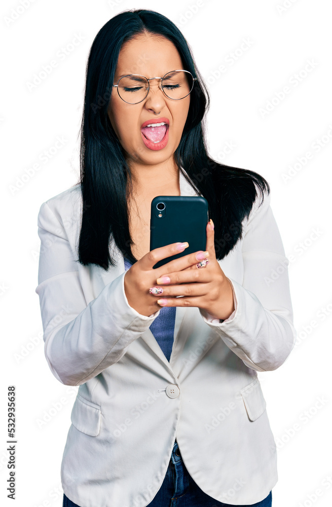 Beautiful hispanic woman with nose piercing using smartphone typing message angry and mad screaming frustrated and furious, shouting with anger. rage and aggressive concept. Beautiful hispanic woman with nose piercing using smartphone typing message angry and mad screaming frustrated and furious, shouting with anger. rage and aggressive concept.