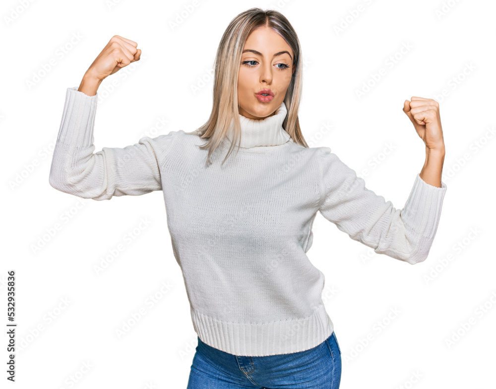 Obraz premium Beautiful blonde woman wearing casual turtleneck sweater showing arms muscles smiling proud. fitness concept.