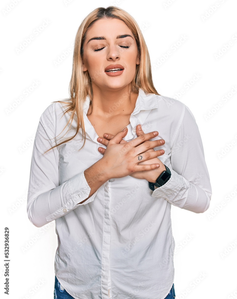 Young caucasian woman wearing casual clothes smiling with hands on chest with closed eyes and grateful gesture on face. health concept. Young caucasian woman wearing casual clothes smiling with hands on chest with closed eyes and grateful gesture on face. health concept.