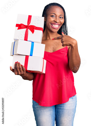 Young african american woman holding gift smiling happy pointing with hand and finger