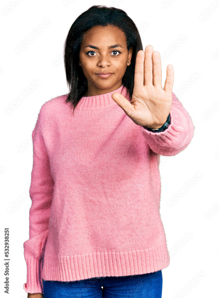 Beautiful hispanic woman wearing casual winter sweater doing stop sing with palm of the hand. warning expression with negative and serious gesture on the face. Beautiful hispanic woman wearing casual winter sweater doing stop sing with palm of the hand. warning expression with negative and serious gesture on the face.