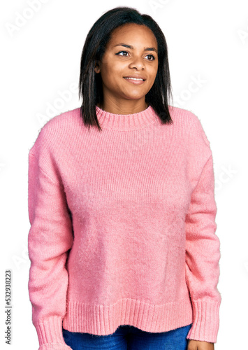 Beautiful hispanic woman wearing casual winter sweater looking away to side with smile on face, natural expression. laughing confident.