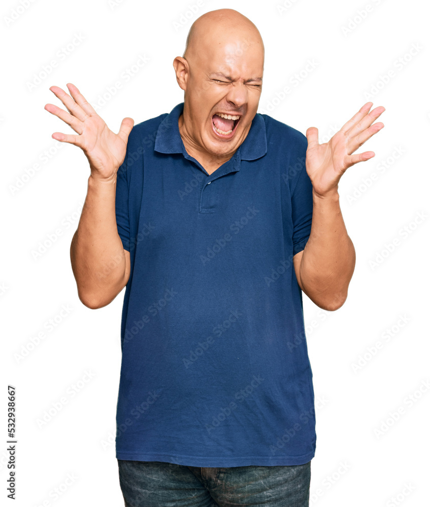 Fototapeta premium Middle age bald man wearing casual clothes celebrating mad and crazy for success with arms raised and closed eyes screaming excited. winner concept
