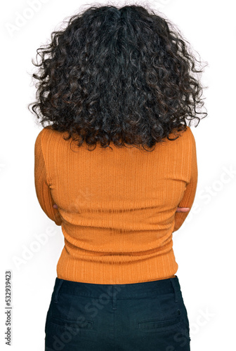 Young hispanic woman wearing casual clothes standing backwards looking away with crossed arms