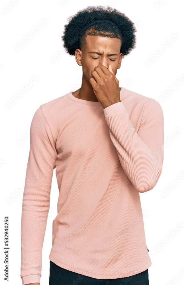 African american man with afro hair wearing casual clothes smelling something stinky and disgusting, intolerable smell, holding breath with fingers on nose. bad smell African american man with afro hair wearing casual clothes smelling something stinky and disgusting, intolerable smell, holding breath with fingers on nose. bad smell