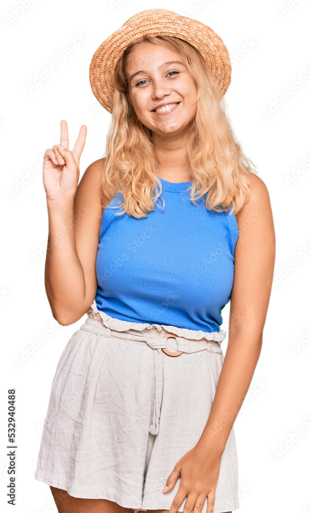 Young blonde girl wearing summer hat smiling with happy face winking at the camera doing victory sign. number two. Young blonde girl wearing summer hat smiling with happy face winking at the camera doing victory sign. number two.
