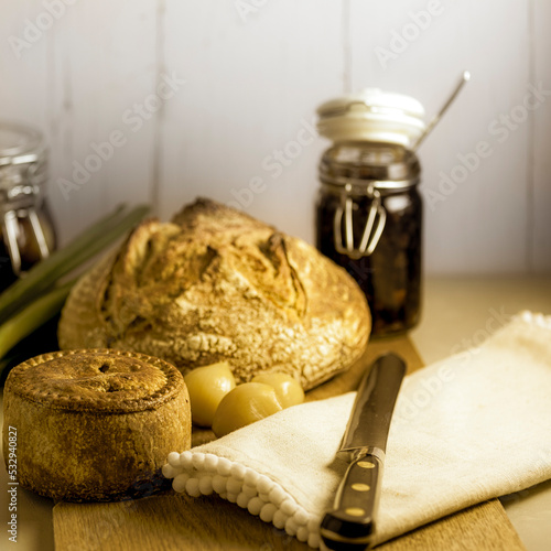 Pork pie and sourdough loaf with picked onions and chutney in a kitchen setting photo