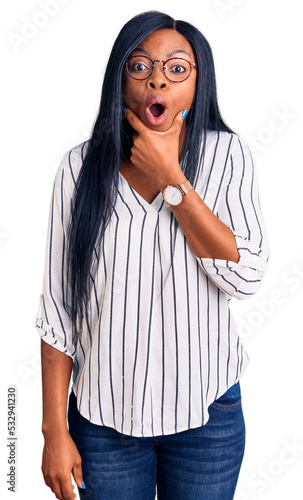 Young african american woman wearing casual clothes and glasses looking fascinated with disbelief, surprise and amazed expression with hands on chin