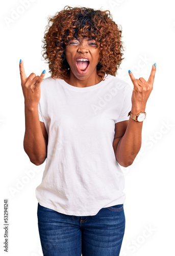 Young african american woman wearing casual white tshirt shouting with crazy expression doing rock symbol with hands up. music star. heavy concept.