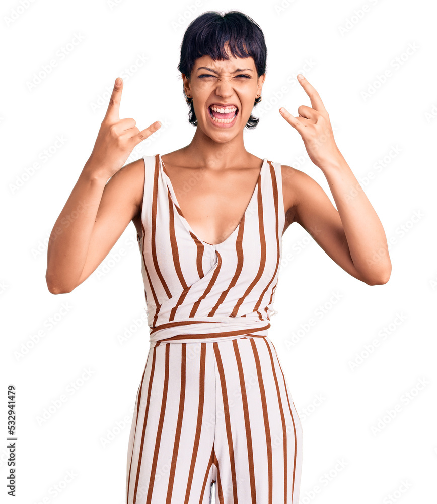 Young brunette woman with short hair wearing summer outfit shouting with crazy expression doing rock symbol with hands up. music star. heavy concept. Young brunette woman with short hair wearing summer outfit shouting with crazy expression doing rock symbol with hands up. music star. heavy concept.