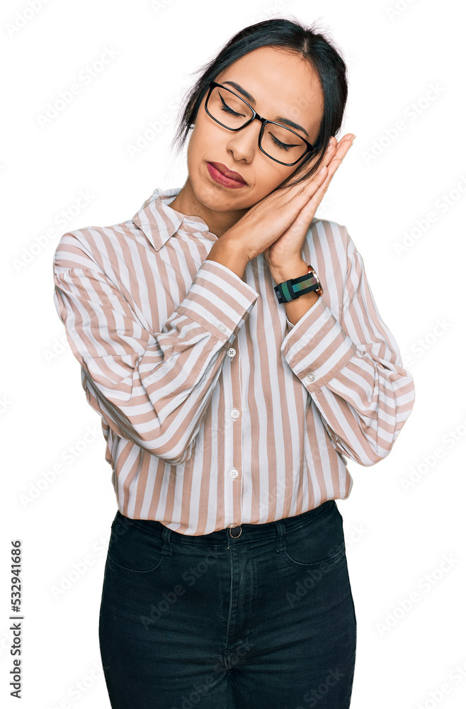 Young hispanic girl wearing casual clothes and glasses sleeping tired dreaming and posing with hands together while smiling with closed eyes.
