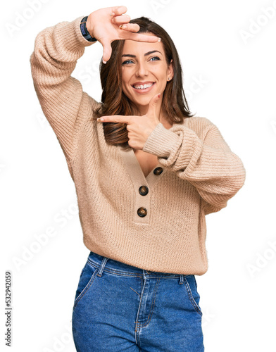 Young brunette woman wearing casual winter sweater smiling making frame with hands and fingers with happy face. creativity and photography concept.