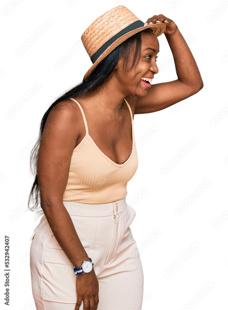 Young black woman wearing summer hat very happy and smiling looking far away with hand over head. searching concept. Young black woman wearing summer hat very happy and smiling looking far away with hand over head. searching concept.