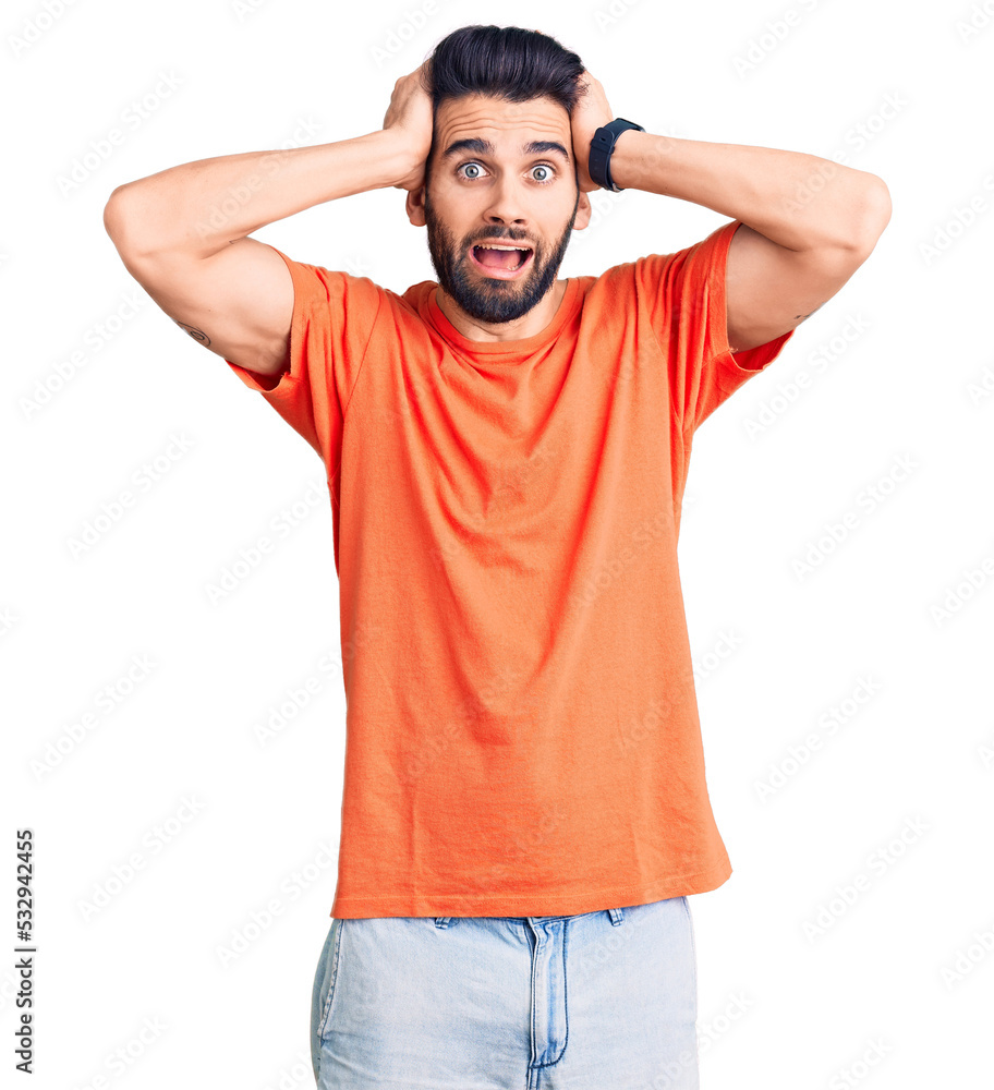 Young handsome man with beard wearing casual t-shirt crazy and scared with hands on head, afraid and surprised of shock with open mouth Young handsome man with beard wearing casual t-shirt crazy and scared with hands on head, afraid and surprised of shock with open mouth