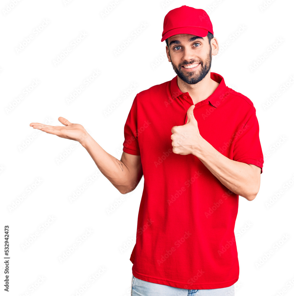 Young handsome man with beard wearing delivery uniform showing palm hand and doing ok gesture with thumbs up, smiling happy and cheerful