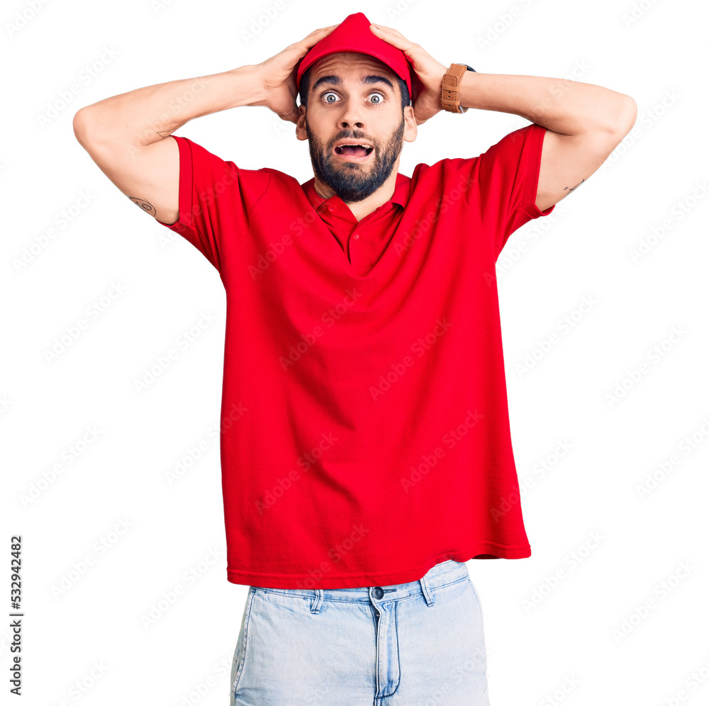 Young handsome man with beard wearing delivery uniform crazy and scared with hands on head, afraid and surprised of shock with open mouth Young handsome man with beard wearing delivery uniform crazy and scared with hands on head, afraid and surprised of shock with open mouth
