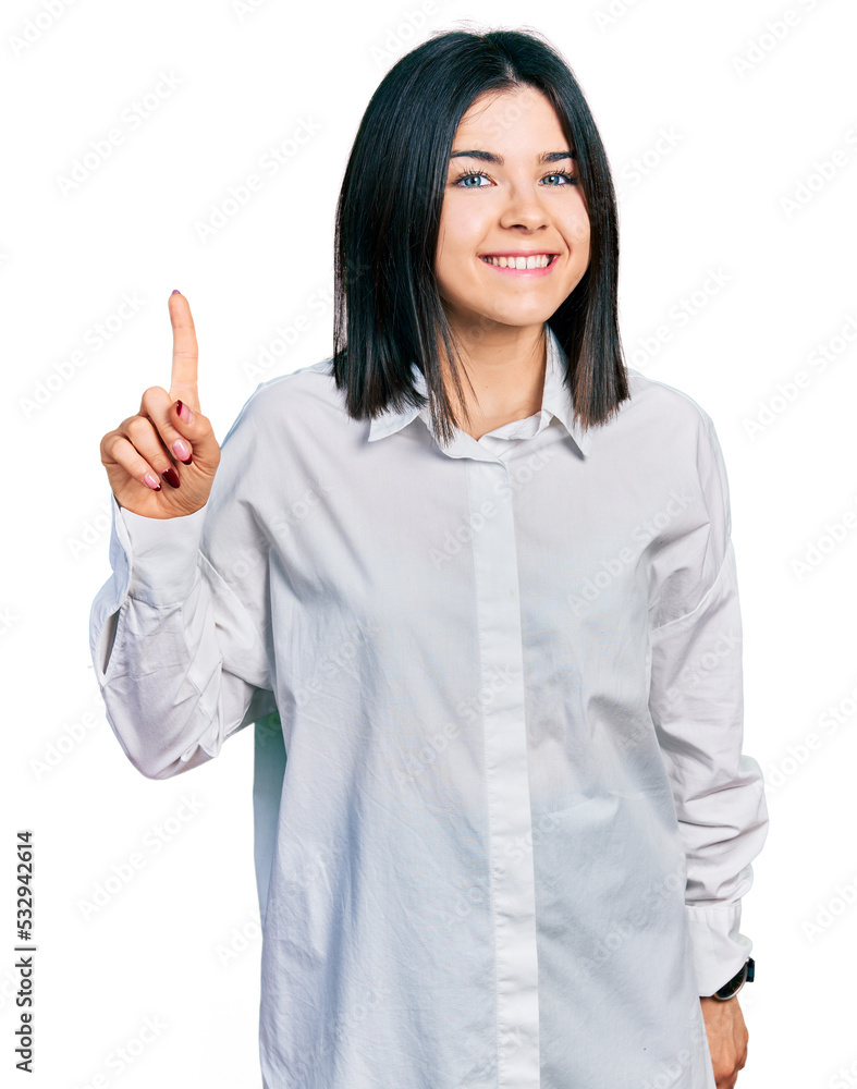 Young brunette woman with blue eyes wearing oversize white shirt showing and pointing up with finger number one while smiling confident and happy. Young brunette woman with blue eyes wearing oversize white shirt showing and pointing up with finger number one while smiling confident and happy.