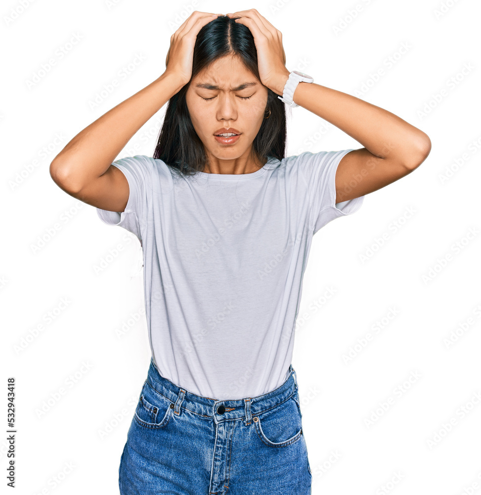 Beautiful young asian woman wearing casual white t shirt suffering from headache desperate and stressed because pain and migraine. hands on head. Beautiful young asian woman wearing casual white t shirt suffering from headache desperate and stressed because pain and migraine. hands on head.