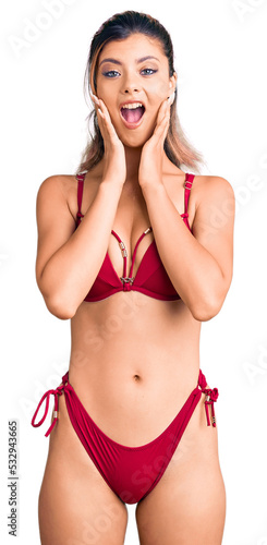 Young beautiful woman wearing bikini afraid and shocked, surprise and amazed expression with hands on face