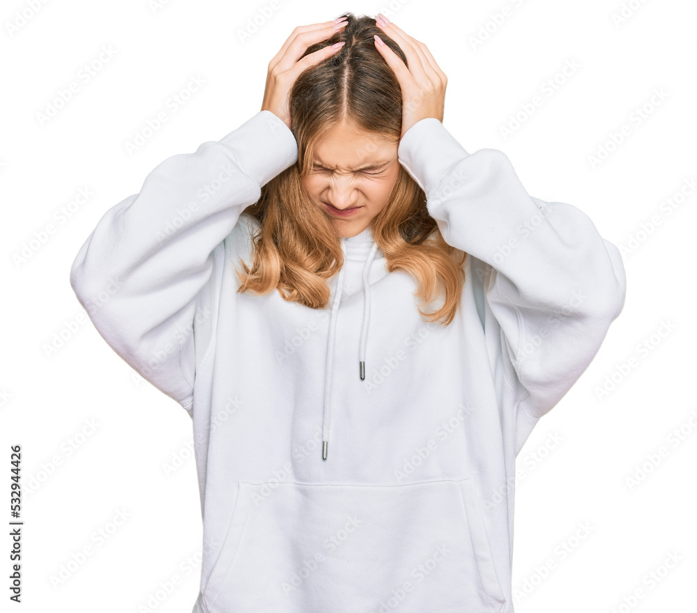 Beautiful young caucasian girl wearing casual sweatshirt suffering from headache desperate and stressed because pain and migraine. hands on head. Beautiful young caucasian girl wearing casual sweatshirt suffering from headache desperate and stressed because pain and migraine. hands on head.