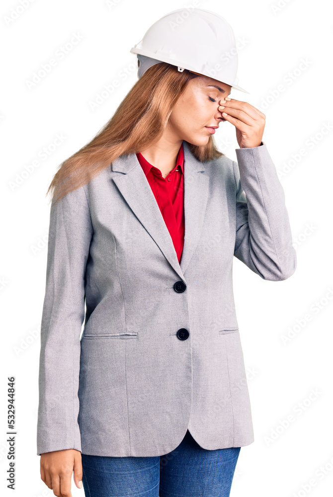 Beautiful young woman wearing architect hardhat tired rubbing nose and eyes feeling fatigue and headache. stress and frustration concept. Beautiful young woman wearing architect hardhat tired rubbing nose and eyes feeling fatigue and headache. stress and frustration concept.