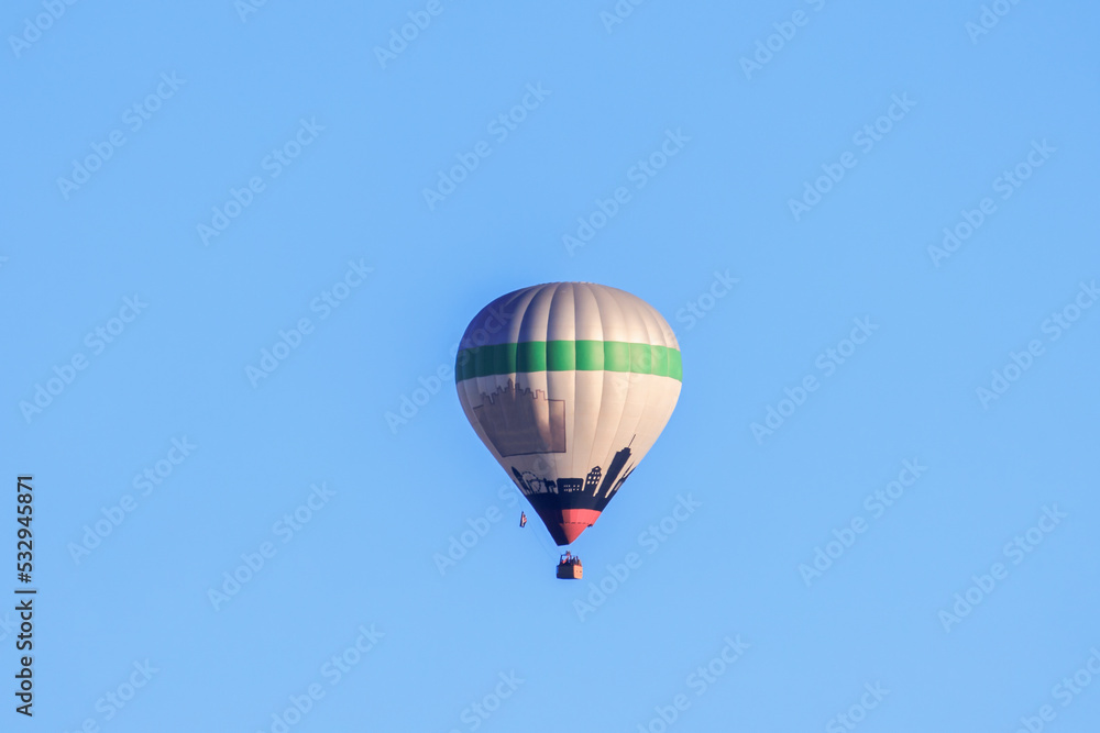 Fototapeta premium A colorful hot air balloon in the morning blue sky over the city of Augsburg