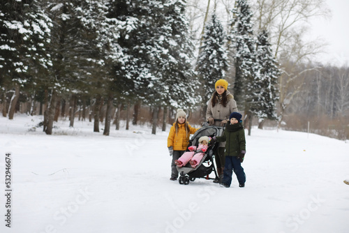 Happy family playing and laughing in winter outdoors in the snow. City park winter day.