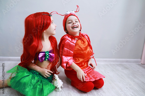 Children in smart carnival costumes on a plain background. Costume of sea fairy creatures. Mermaid and crab. photo