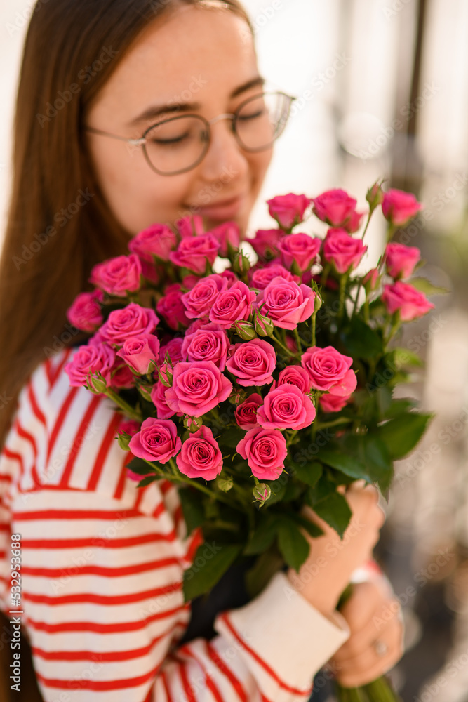 Close-up view of woman tenderly holding and hugging bouquet of bright pink roses Close-up view of woman tenderly holding and hugging bouquet of bright pink roses