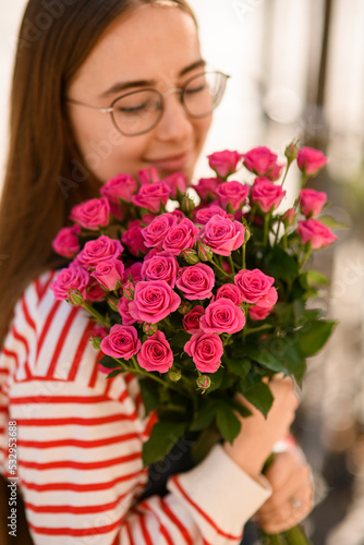 Close-up view of woman tenderly holding and hugging bouquet of bright pink roses
