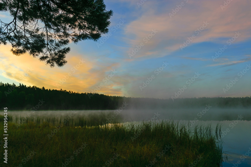 sunrise picture with gorgeous sky, fog covers the surface of the lake, sunrise colored sky