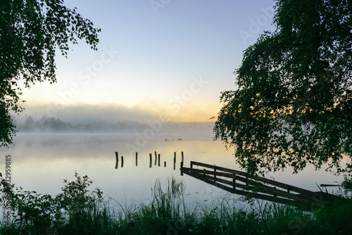 autumn morning by the lake, fog over the surface of the water, a moment before sunrise
